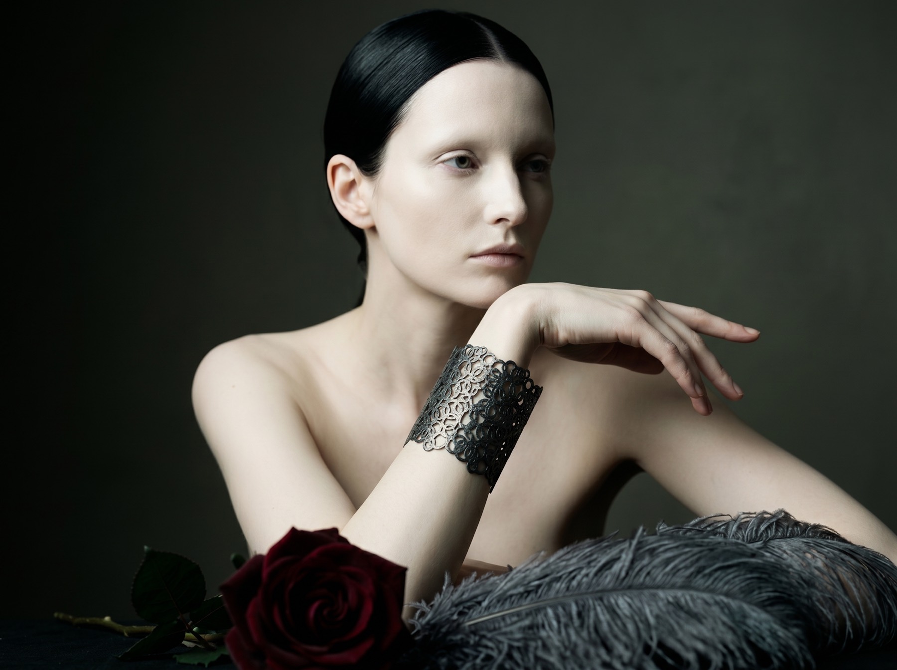 A portrait with an oxidised silver lace cuff and a dark red rose.