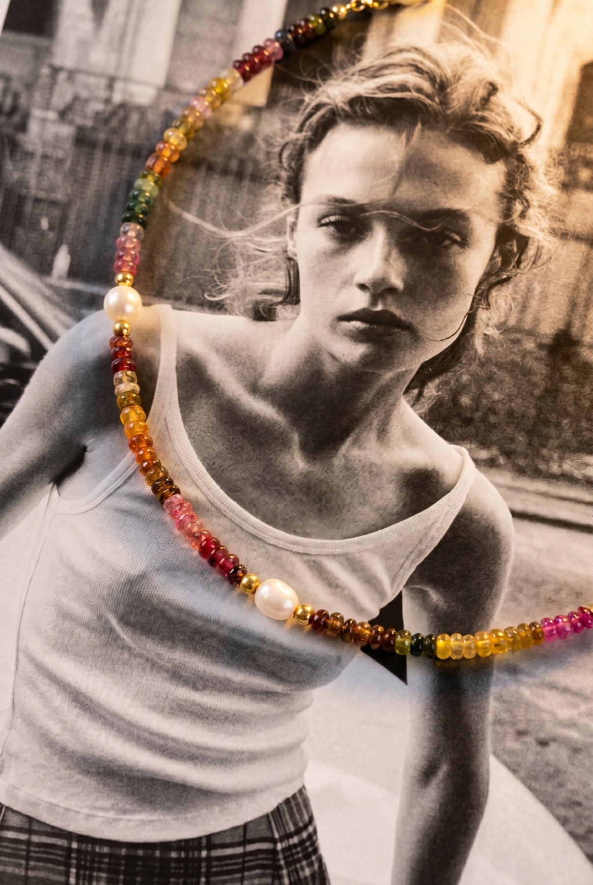 A beaded gemstone necklace worn over a black-and-white portrait.